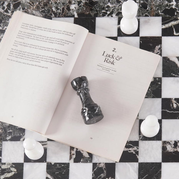 Open book with chess pieces on a checkered marble surface