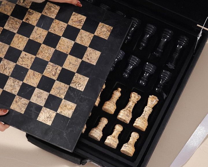 Open chess set with pieces and checkered board in a black box.