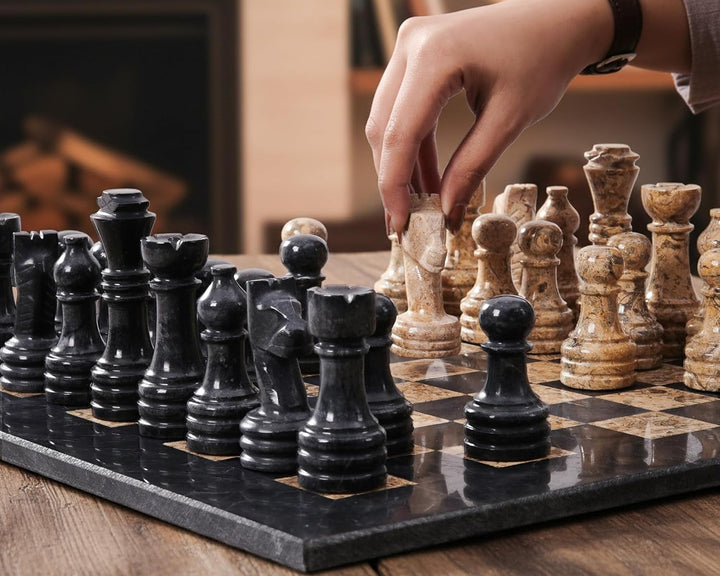 Person playing chess with black and white pieces on a marble board