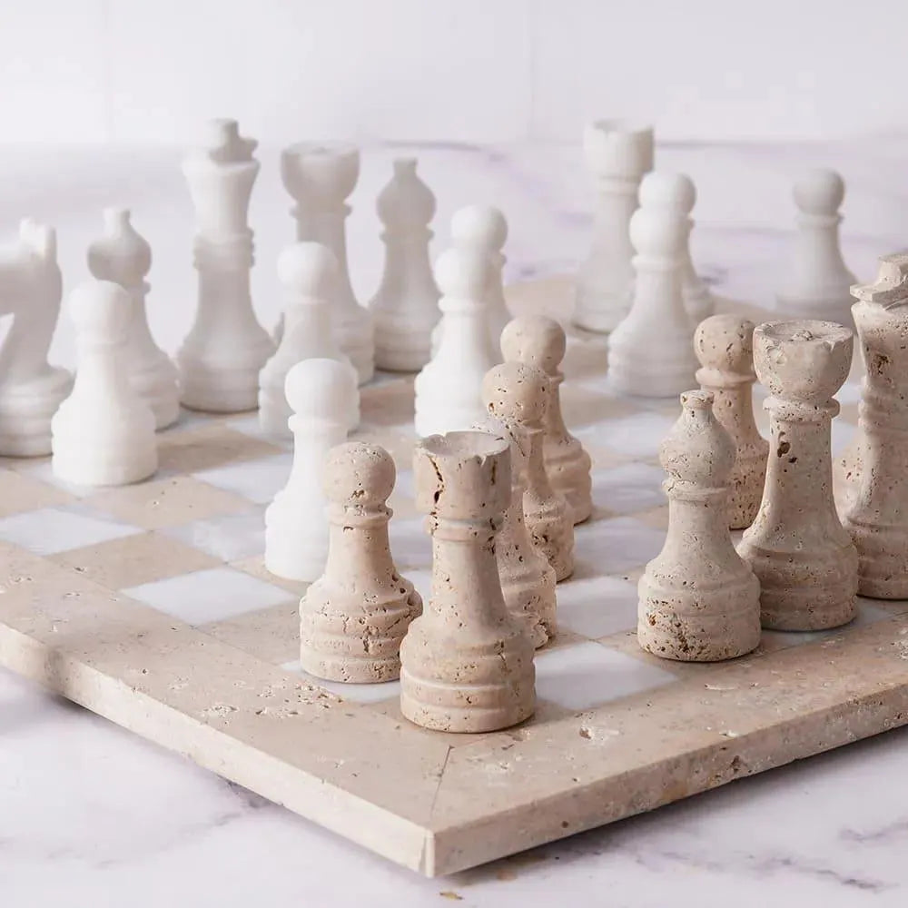 White and beige ceramic chess pieces on a marble chessboard.